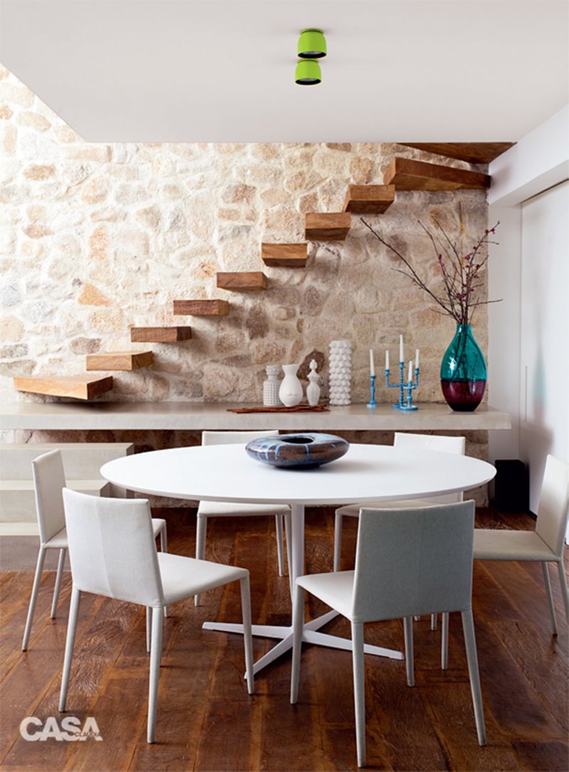 sala de jantar com escada e parede de pedra